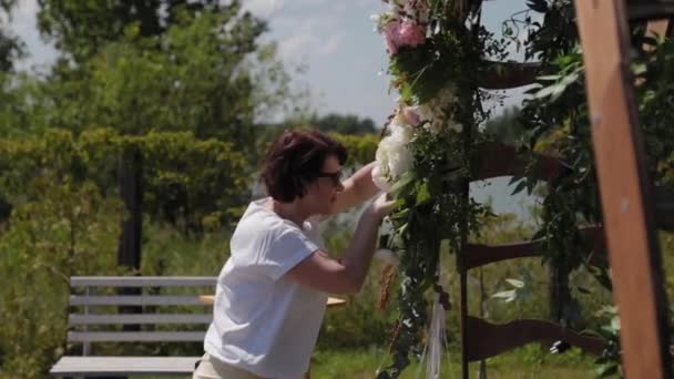 Bruiloft decorateur versiert de plaats van registratie van het huwelijk met verse bloemen. — Stockvideo