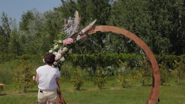 Decorador de bodas decora el lugar de registro del matrimonio con flores frescas . — Vídeo de stock