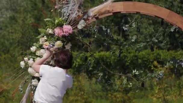 Decorador de bodas decora el lugar de registro del matrimonio con flores frescas . — Vídeo de stock