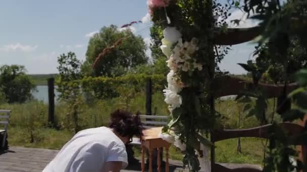 Bruiloft decorateur versiert de plaats van registratie van het huwelijk met verse bloemen. — Stockvideo