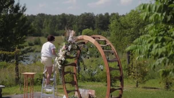 Bruiloft decorateur versiert de plaats van registratie van het huwelijk met verse bloemen. — Stockvideo