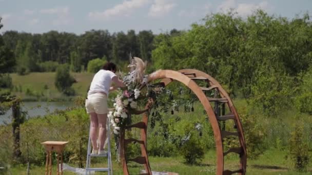 Decorador de bodas decora el lugar de registro del matrimonio con flores frescas . — Vídeo de stock