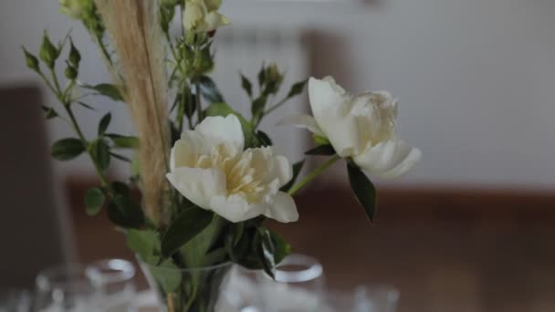 Красиві квіти в скляній вазі на святковому столі . — стокове відео