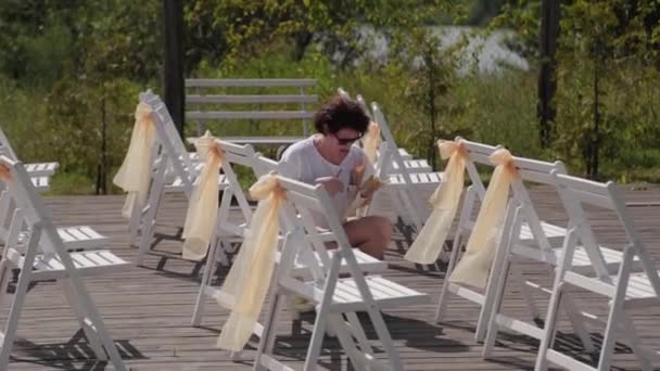 Woman decorator decorates chairs at the wedding registration. — Stock Video