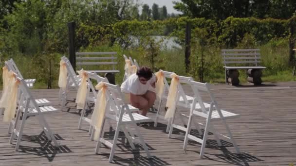 Mujer decorador decora sillas en el registro de la boda . — Vídeos de Stock