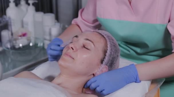 Profesionální kosmetička nasazuje klobouk na klienta na ženu. — Stock video