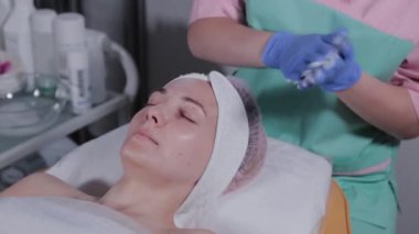 Profesyonel güzellik uzmanı eldivenlere jöle sürer ve ovalar..