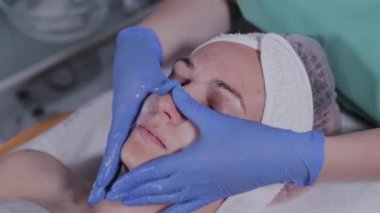 Profesyonel güzellik uzmanı bir kadını yıkar ve yüzüne masaj yapar..