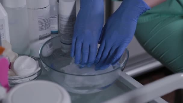Профессиональный косметолог увлажняет салфетки в теплой воде, чтобы умыть лицо. — стоковое видео