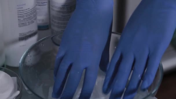En professionell kosmetolog fuktar våtservetter i varmt vatten för att tvätta ansiktet. — Stockvideo