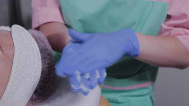 Professionelle Kosmetikerin zieht Gel auf Handschuhe und reibt es ein. — Stockvideo