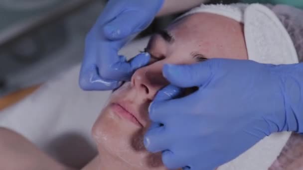 Professionele schoonheidsspecialiste wast een vrouw en masseert haar gezicht. — Stockvideo