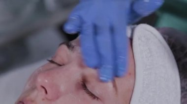 Profesyonel güzellik uzmanı bir kadını yıkar ve yüzüne masaj yapar..