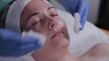 Profesyonel güzellik uzmanı bir kadının maskesini yıkar..