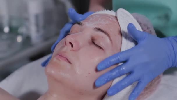 Επαγγελματίας αισθητικός πλένει μια γυναίκα και κάνει μασάζ στο πρόσωπό της. — Αρχείο Βίντεο