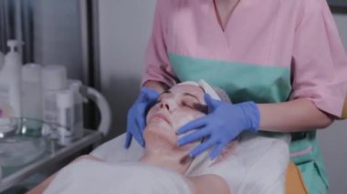 Profesyonel bir güzellik uzmanı bir kadına yüz masajı yapar. Kozmetoloji.