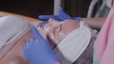 Profesyonel bir güzellik uzmanı bir kadına yüz masajı yapar. Kozmetoloji.