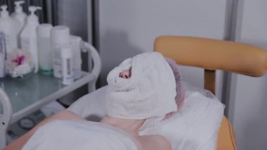 Güzellik salonunda bir kadının yüzüne sıcak beyaz bir havlu..