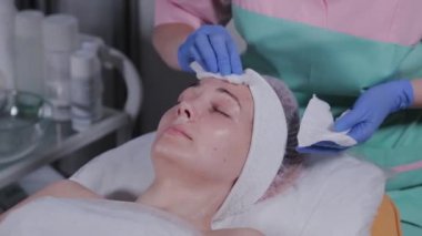 Profesyonel güzellik uzmanı bir kadının maskesini yıkar..