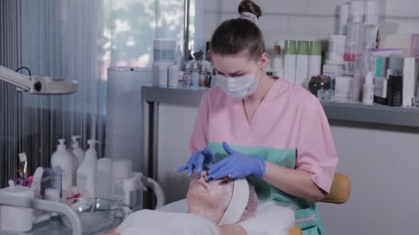 Eine professionelle Kosmetikerin macht eine Gesichtsmassage für eine Frau. Kosmetologie. — Stockvideo