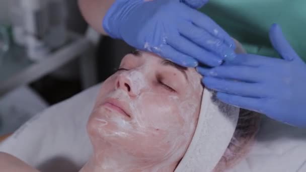 Een professionele schoonheidsspecialiste doet gezichtsmassage bij een vrouw. Cosmetologie. — Stockvideo