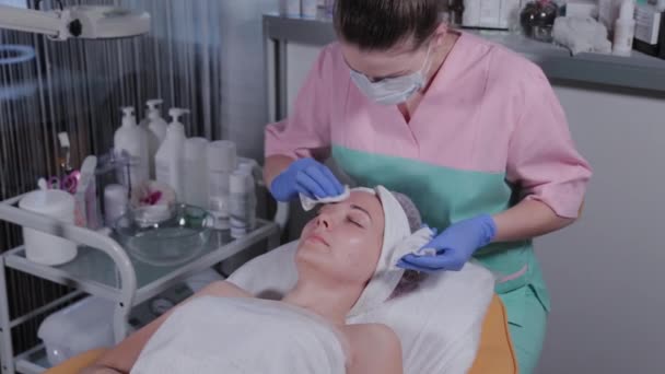 Profesjonalny kosmetyk zmywa maskę z twarzy kobiety.. — Wideo stockowe