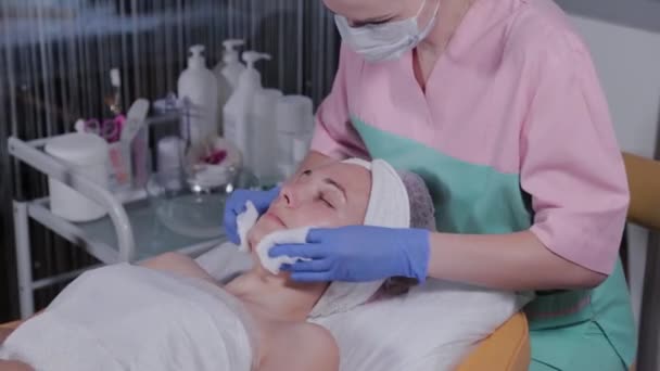 Profesjonalny kosmetyk zmywa maskę z twarzy kobiety.. — Wideo stockowe