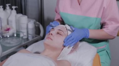 Güzellik uzmanı güzellik salonunda bir kadına yüz masajı yapıyor..