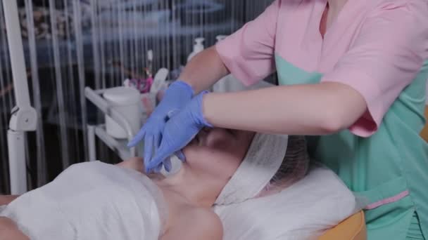 Косметик делает массаж лица женщине в салоне красоты . — стоковое видео