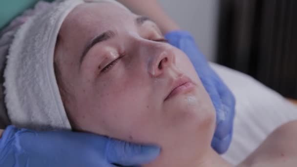 Güzellik uzmanı güzellik salonunda bir kadına yüz masajı yapıyor.. — Stok video