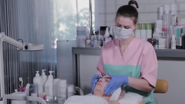 Kosmetička dělá masáž obličeje na ženu v salónu krásy. — Stock video