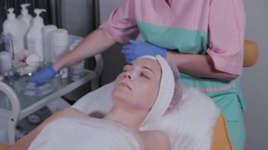 Profesyonel güzellik uzmanı bir kadının maskesini yıkar..