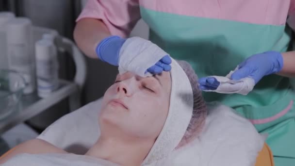 Esteticista profesional lava la máscara de la cara de una mujer . — Vídeo de stock