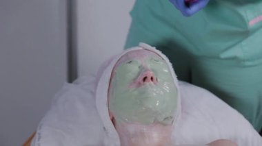 Profesyonel, bir kadına yüz maskesi takar..