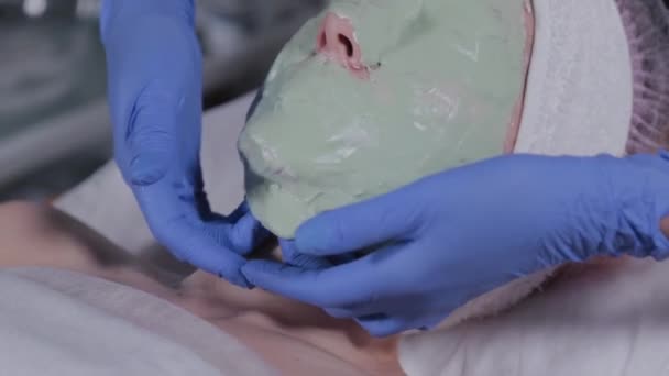 Esteticista profissional remove a máscara do rosto de uma mulher . — Vídeo de Stock