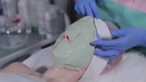 Esteticista profissional remove a máscara do rosto de uma mulher . — Vídeo de Stock