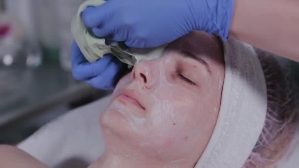 Profesionální kosmetička odstraní masku z tváře ženy. — Stock video