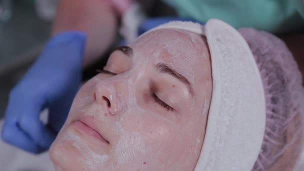 Esthéticienne professionnelle lave le masque sur le visage d'une femme. — Video