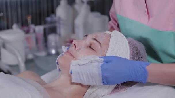 Estetista professionista lava la maschera dal viso di una donna. — Video Stock