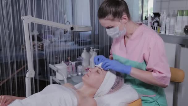 Professionelle Kosmetikerin wäscht einer Frau die Maske vom Gesicht. — Stockvideo