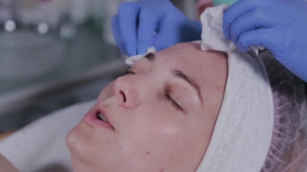 Esthéticienne professionnelle lave le masque sur le visage d'une femme. — Video