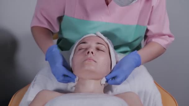 Profesionální kosmetička smyje masku z tváře ženy. — Stock video