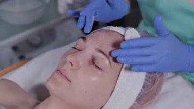 Profesyonel güzellik uzmanı güzellik salonunda bir kadına yüz masajı yapar..