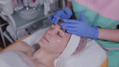 Profesyonel güzellik uzmanı güzellik salonunda bir kadına yüz masajı yapar..