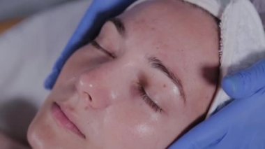 Profesyonel güzellik uzmanı güzellik salonunda bir kadına yüz masajı yapar..