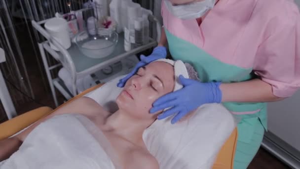 Професійний косметолог робить масаж обличчя жінці в салоні краси . — стокове відео