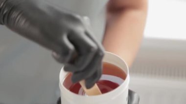 Kozmetikçi kavanozdaki şeker macununu alıyor. Shugaring. Konteynırdan bir spatula ile şeker ezmesi. Şekerleme için şeker ezmesi. Güzellik salonunda şekerleme.