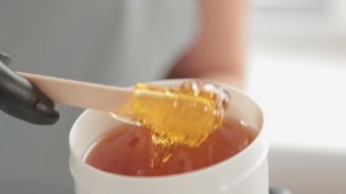 Kozmetikçi kavanozdaki şeker macununu alıyor. Shugaring. Konteynırdan bir spatula ile şeker ezmesi. Şekerleme için şeker ezmesi. Güzellik salonunda şekerleme.