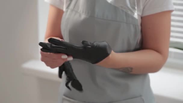 Esthéticienne met des gants en caoutchouc noir sur ses mains. — Video