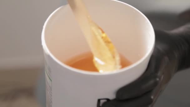 Cosmétique prend la pâte de sucre du pot. Je tremble. Pâte à sucre sortie du récipient avec une spatule. Pâte à sucre pour le sucre. Sucrer dans un salon de beauté. — Video